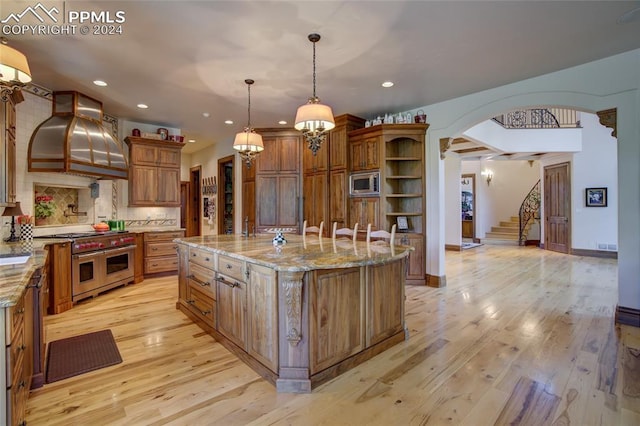 4950 Longwood Pt, Colorado Springs, CO 80906 - kitchen with brown cabinets, stainless steel appliances, light wood-style floors, premium range hood, and open shelves