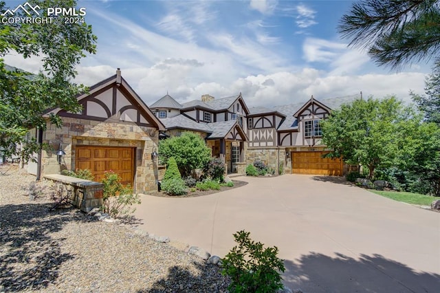 exterior space with stone siding, an attached garage, and concrete driveway