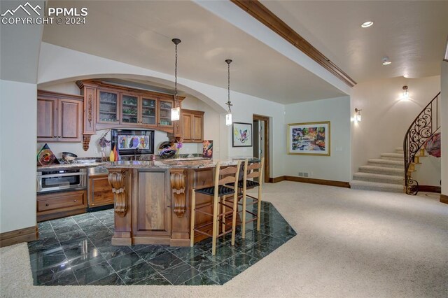 4950 Longwood Pt, Colorado Springs, CO 80906 - kitchen featuring light stone counters, dark carpet, brown cabinetry, glass insert cabinets, and a kitchen bar