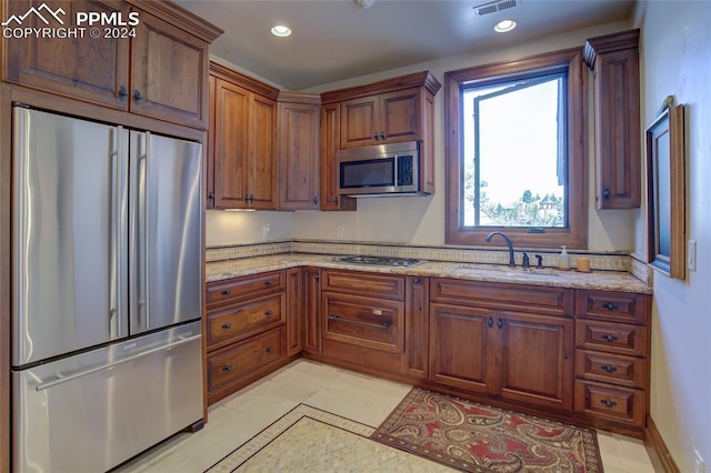 4950 Longwood Pt, Colorado Springs, CO 80906 - kitchen with appliances with stainless steel finishes, brown cabinets, light stone counters, a sink, and recessed lighting