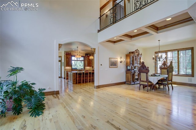 4950 Longwood Pt, Colorado Springs, CO 80906 - interior space featuring arched walkways, a notable chandelier, light wood-style flooring, a high ceiling, and baseboards