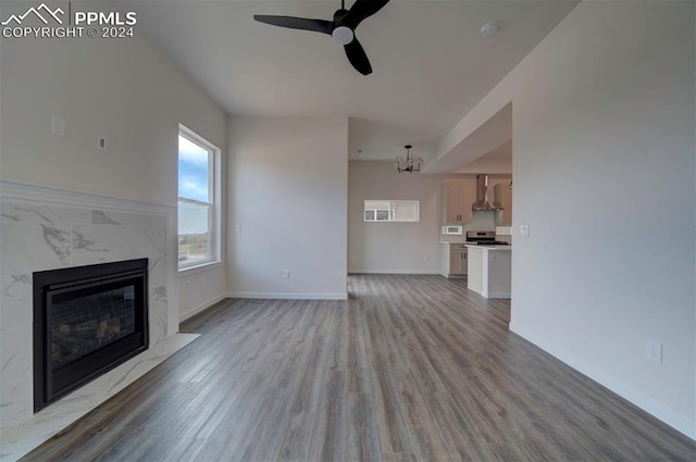 unfurnished living room featuring ceiling fan with notable chandelier, light hardwood / wood-style flooring, and a premium fireplace