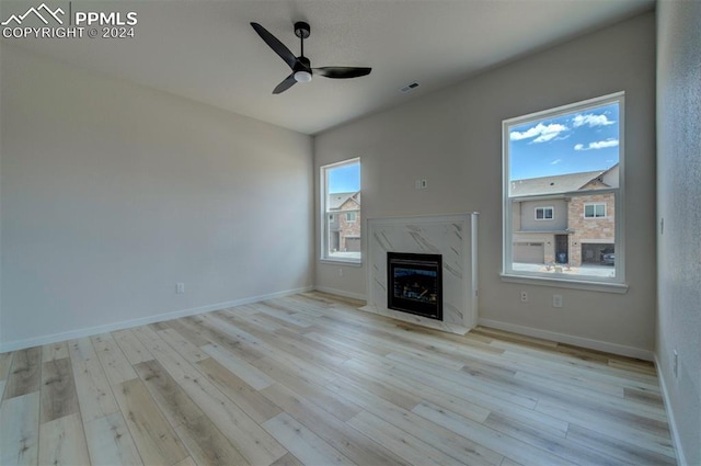 unfurnished living room featuring ceiling fan, a fireplace, and light hardwood / wood-style flooring