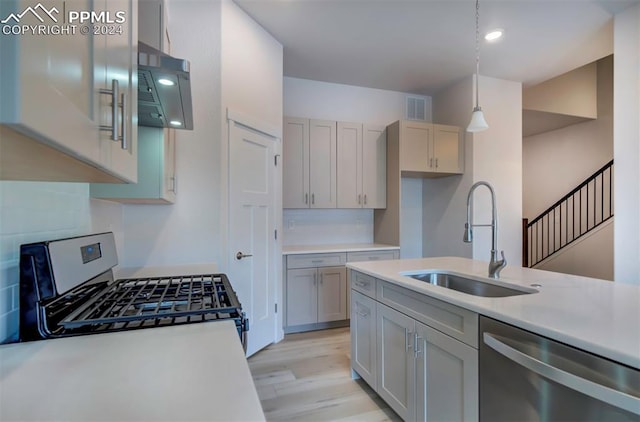 kitchen featuring decorative light fixtures, gray cabinets, light hardwood / wood-style floors, sink, and appliances with stainless steel finishes