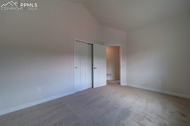 unfurnished bedroom featuring light colored carpet and high vaulted ceiling