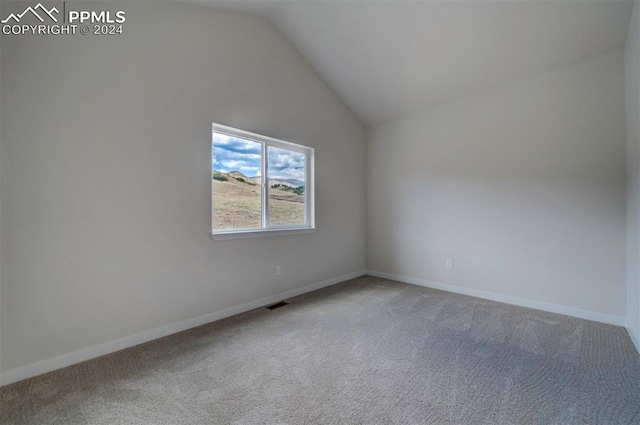 carpeted spare room with vaulted ceiling