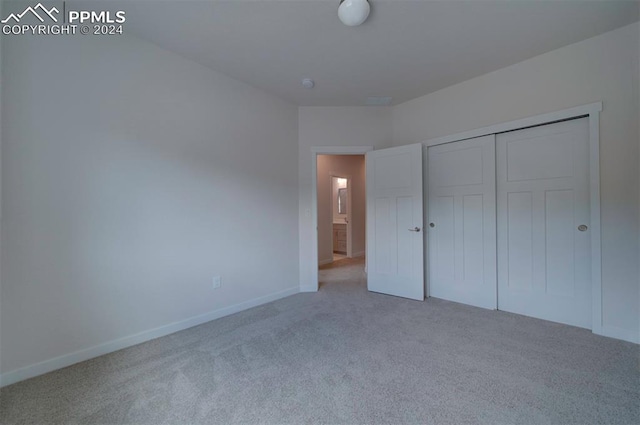 unfurnished bedroom featuring a closet and light carpet