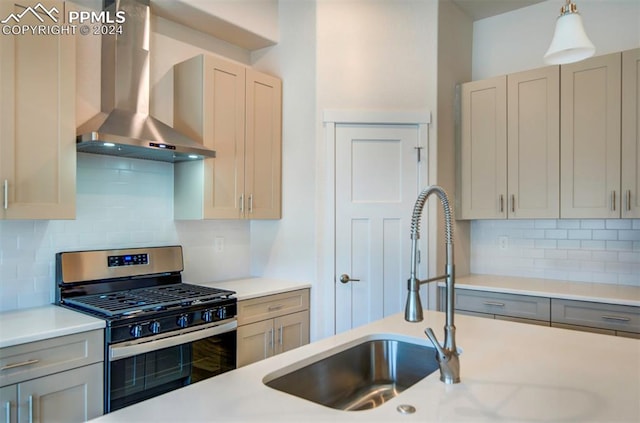 kitchen with decorative light fixtures, tasteful backsplash, stainless steel range with gas stovetop, and wall chimney range hood