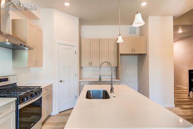 kitchen with decorative light fixtures, light hardwood / wood-style floors, sink, wall chimney exhaust hood, and gas range