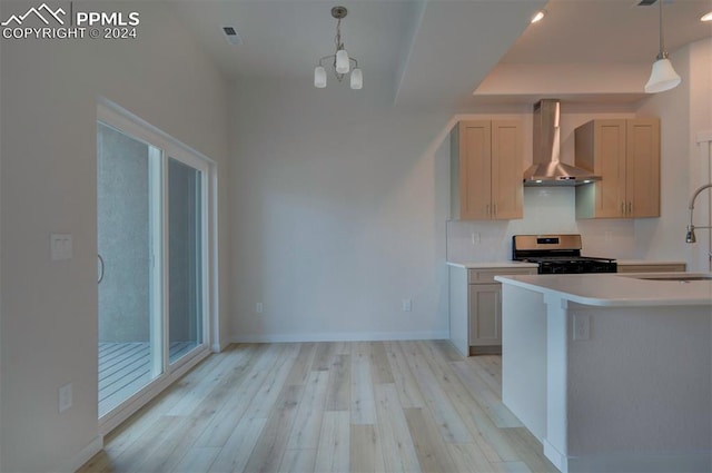 kitchen featuring pendant lighting, stainless steel stove, wall chimney range hood, and an inviting chandelier