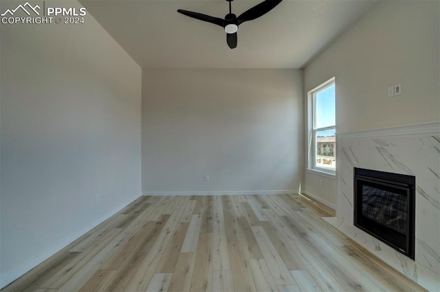 unfurnished living room featuring ceiling fan, a high end fireplace, and light hardwood / wood-style floors