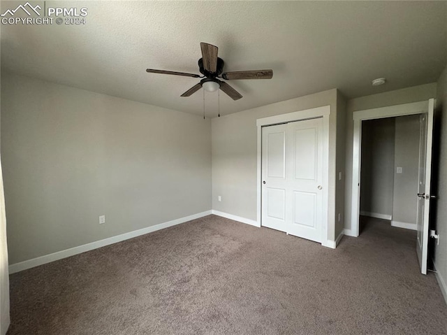 unfurnished bedroom with ceiling fan, a textured ceiling, a closet, and dark colored carpet