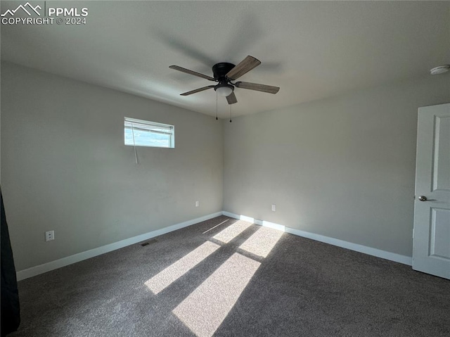 empty room featuring ceiling fan and dark colored carpet