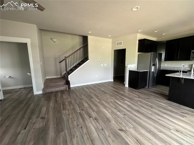 kitchen with hardwood / wood-style flooring, light stone countertops, sink, and stainless steel appliances