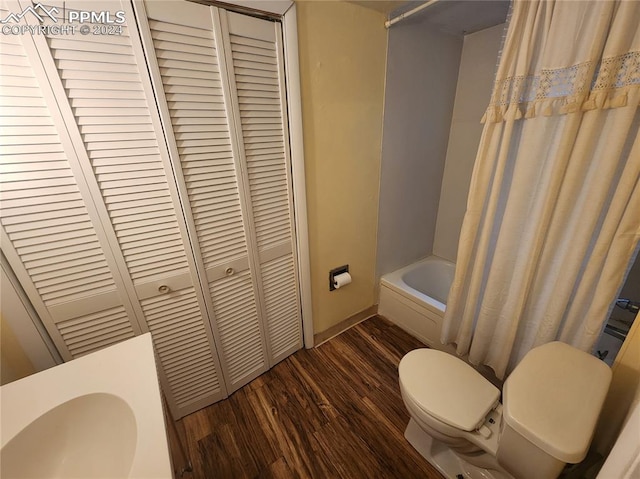 bathroom featuring hardwood / wood-style flooring, shower / bath combo with shower curtain, and toilet