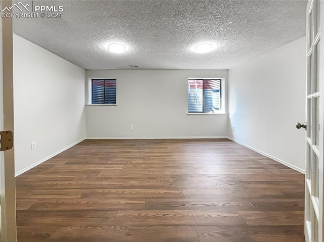 unfurnished room with a textured ceiling and dark hardwood / wood-style flooring