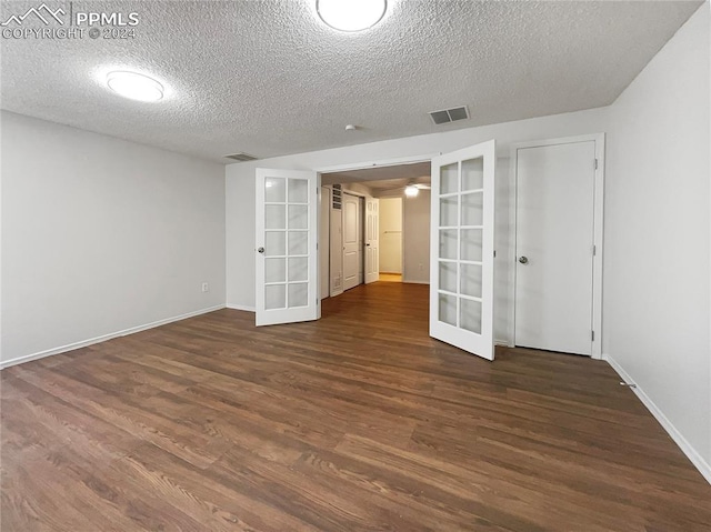 empty room featuring a textured ceiling, dark hardwood / wood-style floors, and french doors