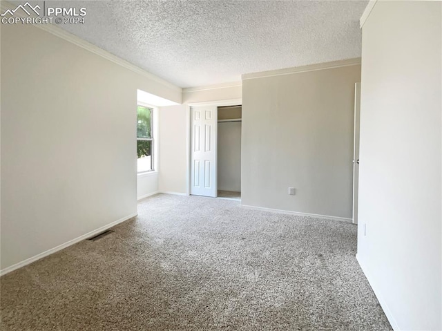 unfurnished bedroom with a closet, a textured ceiling, carpet floors, and crown molding