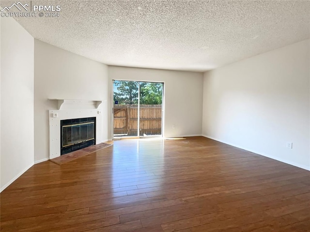 unfurnished living room featuring dark wood-type flooring and a textured ceiling