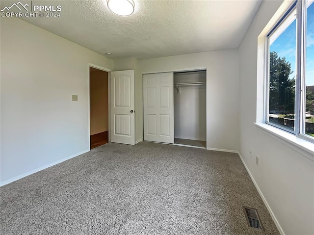 unfurnished bedroom with a textured ceiling, a closet, and carpet flooring