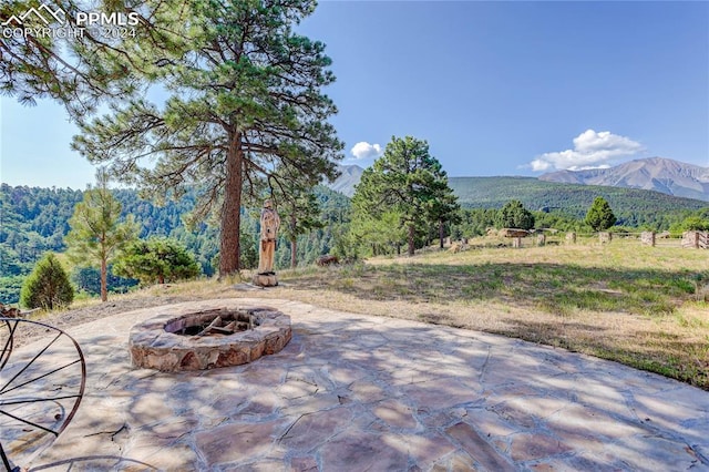 view of patio with an outdoor fire pit, a mountain view, and a forest view