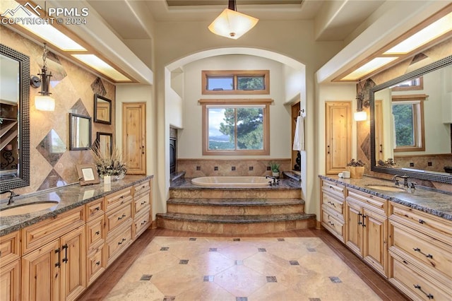 bathroom with tasteful backsplash, two vanities, a sink, and a bath