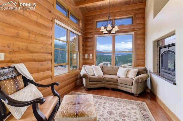 interior space with wooden ceiling, wood finished floors, beam ceiling, a glass covered fireplace, and an inviting chandelier