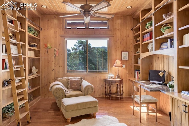 living area with ceiling fan, wood walls, wood finished floors, and wood ceiling