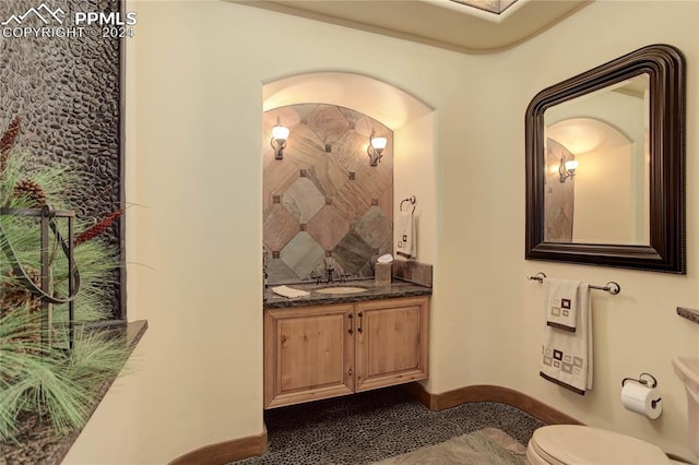 bathroom featuring toilet, tasteful backsplash, vanity, and baseboards