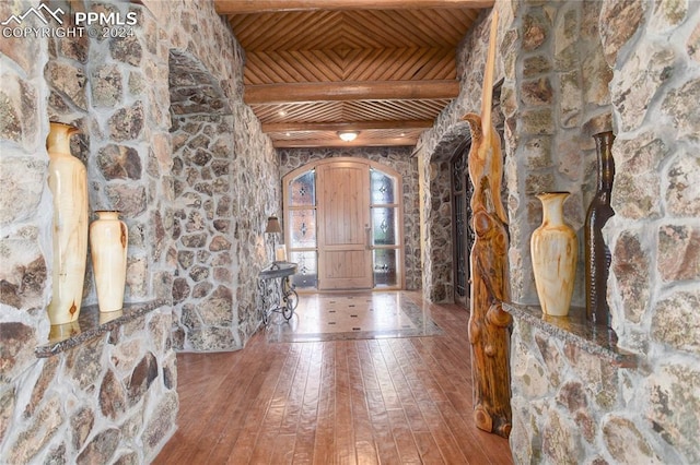 foyer featuring arched walkways, wooden ceiling, beamed ceiling, and hardwood / wood-style flooring