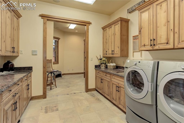 washroom featuring washing machine and dryer, cabinet space, and baseboards