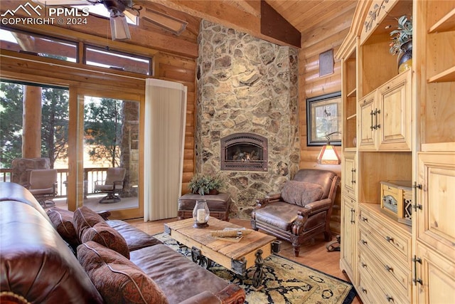 living area featuring vaulted ceiling with beams, a stone fireplace, wood ceiling, a ceiling fan, and light wood-type flooring