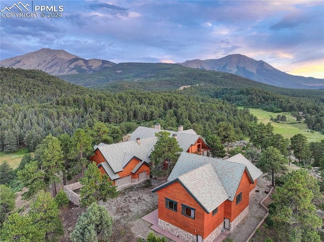 aerial view at dusk featuring a mountain view and a forest view