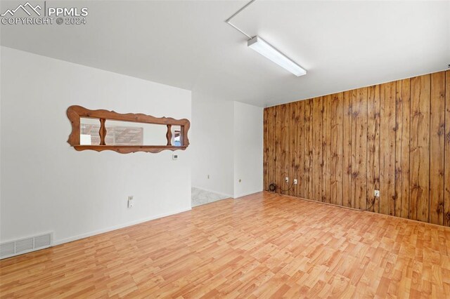 spare room featuring hardwood / wood-style floors and wooden walls