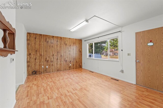 unfurnished room featuring hardwood / wood-style floors and wooden walls