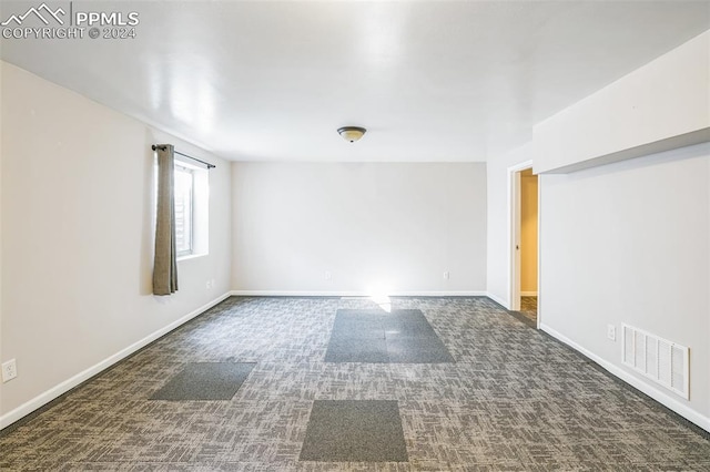 unfurnished room with dark colored carpet