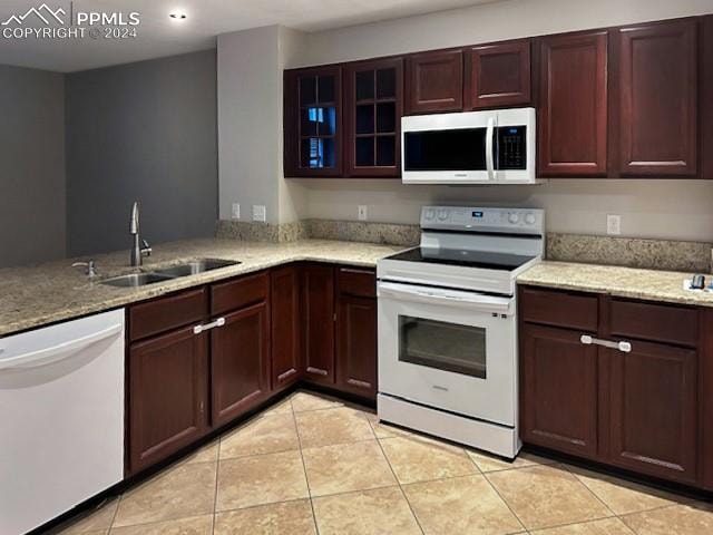 kitchen featuring white appliances, light tile patterned floors, light stone countertops, and sink