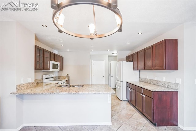 kitchen with sink, light stone counters, white appliances, and kitchen peninsula