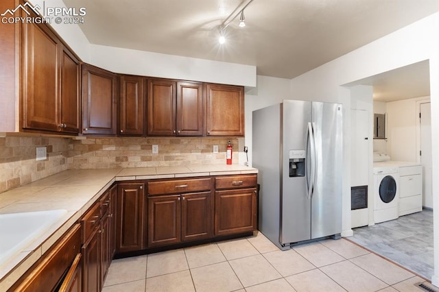 kitchen with washer and clothes dryer, rail lighting, light tile patterned floors, sink, and stainless steel refrigerator with ice dispenser