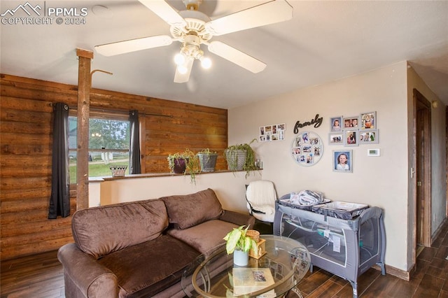 living area featuring a ceiling fan, log walls, and wood finished floors