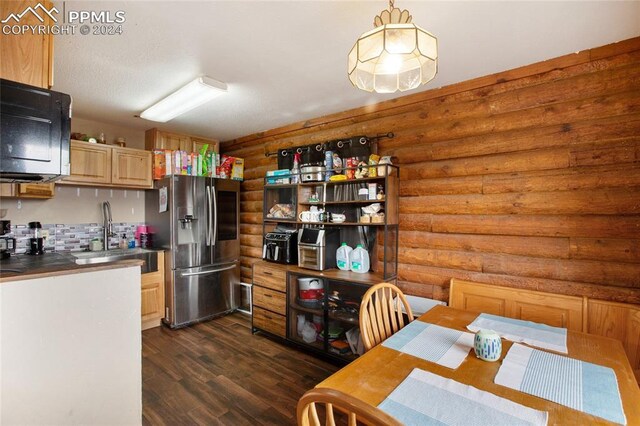 kitchen with rustic walls, dark wood-type flooring, decorative light fixtures, and stainless steel refrigerator with ice dispenser