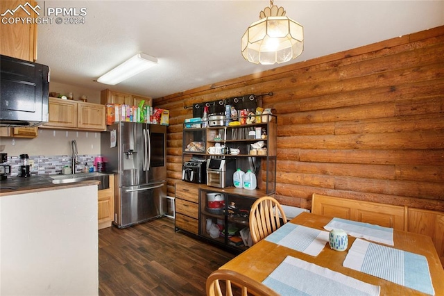 kitchen with dark wood-style floors, dark countertops, rustic walls, a sink, and stainless steel fridge with ice dispenser