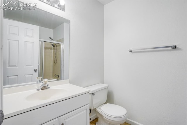 bathroom with baseboards, tiled shower, vanity, and toilet