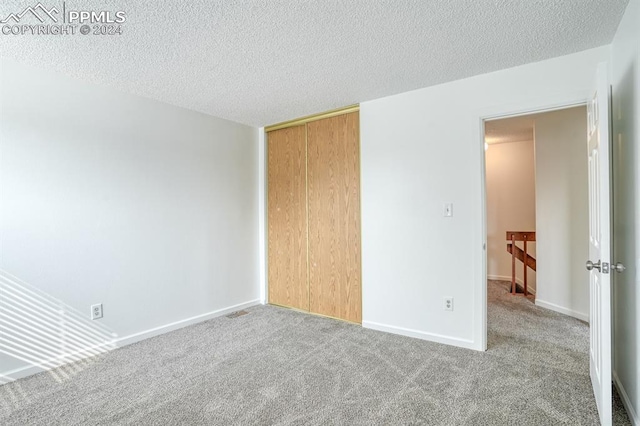 empty room featuring carpet flooring, a textured ceiling, and baseboards