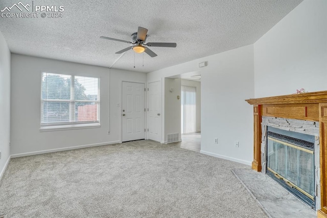 unfurnished living room with baseboards, ceiling fan, a textured ceiling, carpet floors, and a fireplace