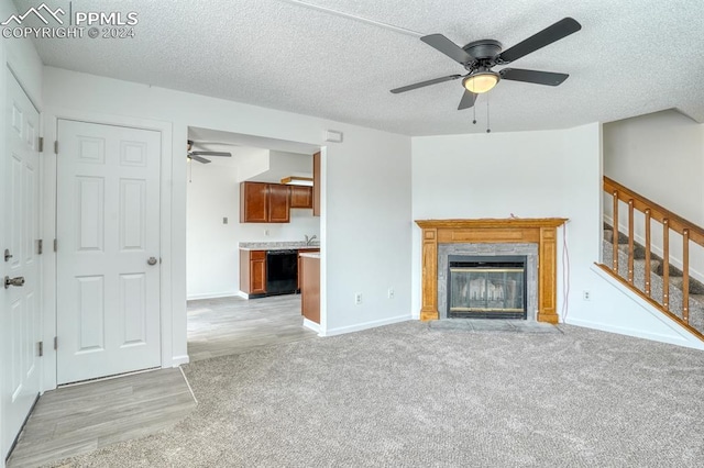 unfurnished living room with light carpet, stairway, a fireplace, and a textured ceiling