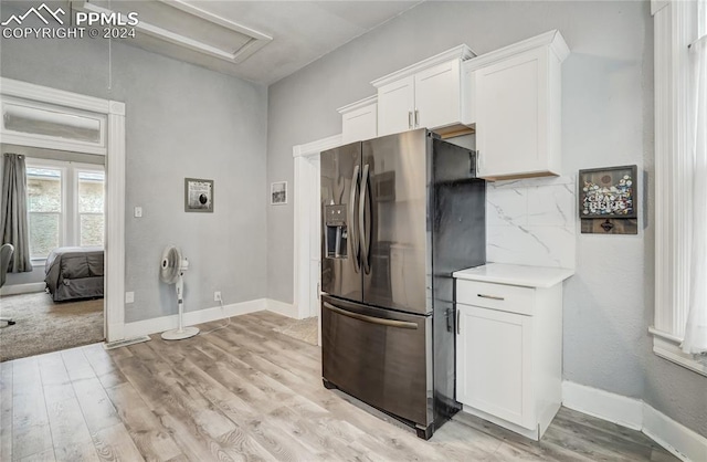 kitchen featuring tasteful backsplash, light hardwood / wood-style flooring, white cabinets, and stainless steel refrigerator with ice dispenser