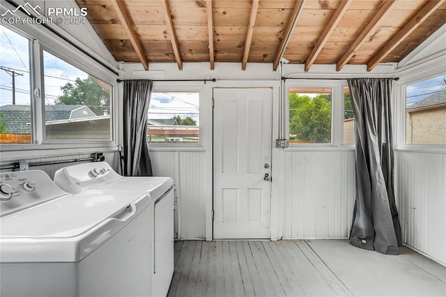 washroom featuring wood ceiling, washer and clothes dryer, wooden walls, and a wealth of natural light