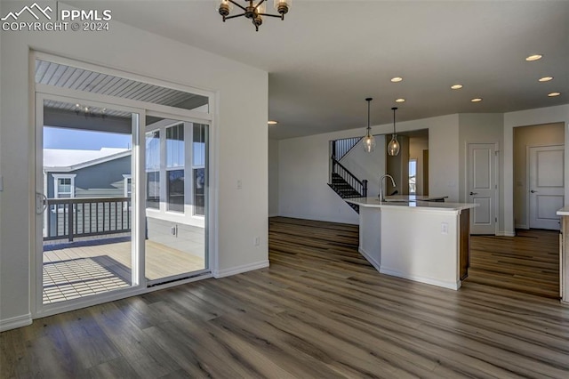 kitchen featuring pendant lighting, dark hardwood / wood-style flooring, a center island with sink, and an inviting chandelier