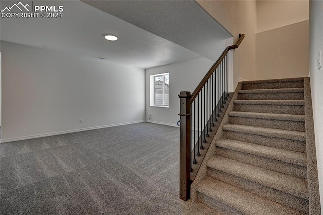 stairway featuring baseboards and carpet floors